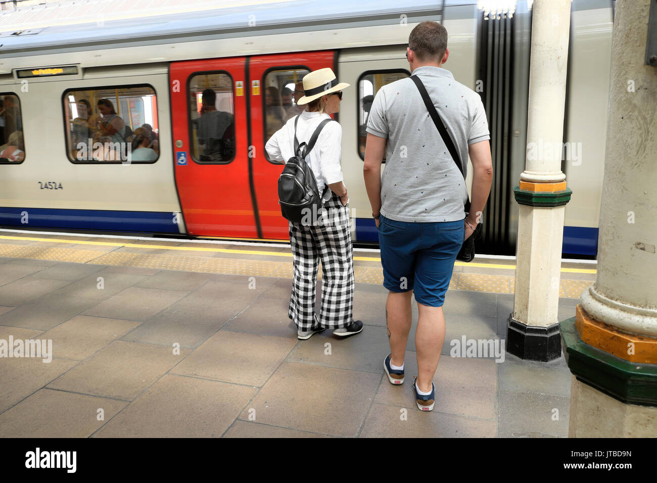 En été femme hat et vérifier sur la plate-forme d'attente pantalon à High Street Kensington station de métro dans l'ouest de Londres, UK KATHY DEWITT Banque D'Images