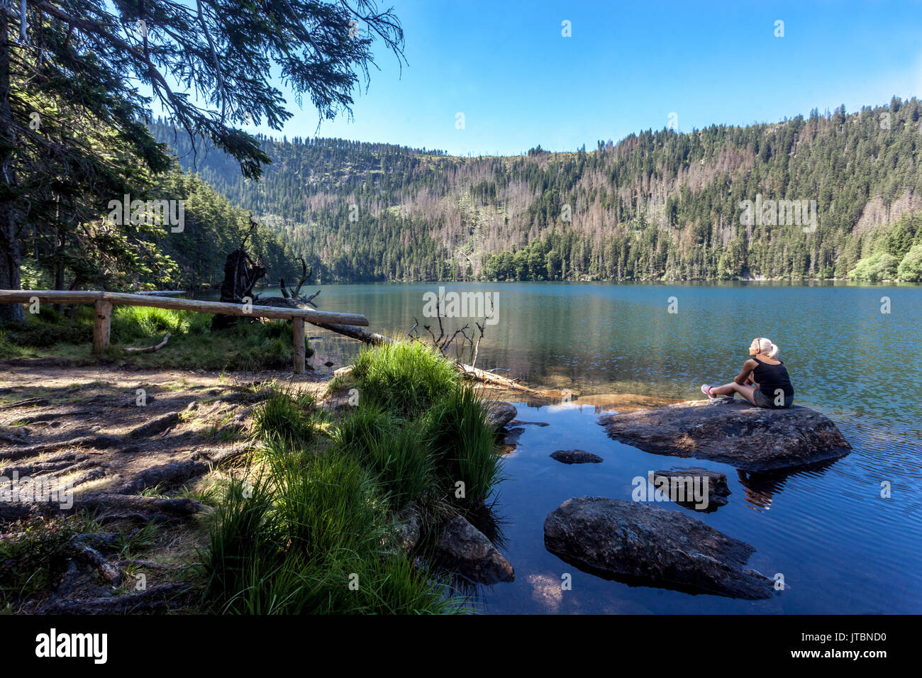 Lac noir glaciaire, cerne jezero dans les montagnes de Sumava, parc national, République tchèque. Femme assise sur la pierre seule Banque D'Images