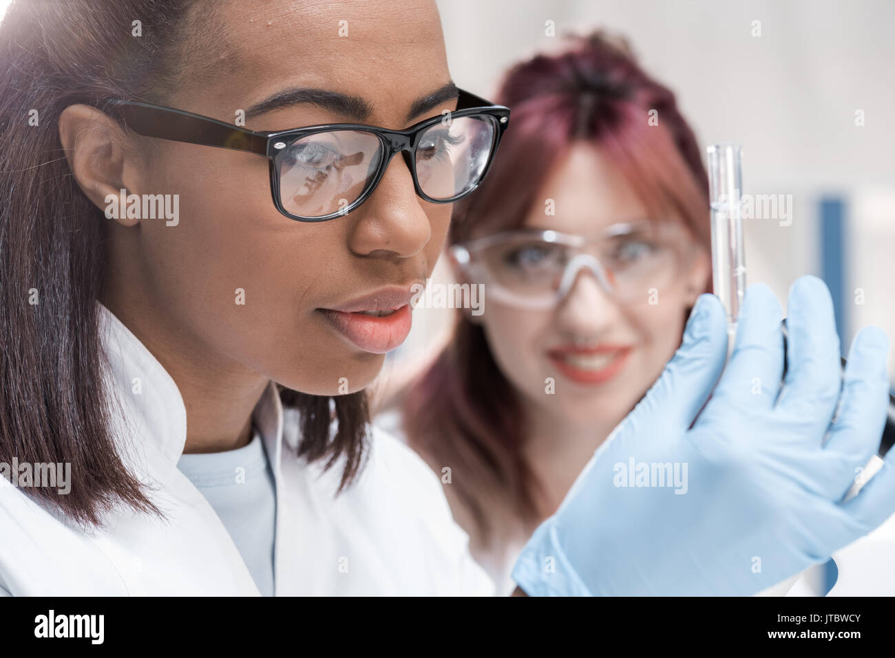 Les jeunes scientifiques à lunettes à la recherche de tube à essai en laboratoire chimique réactif Banque D'Images