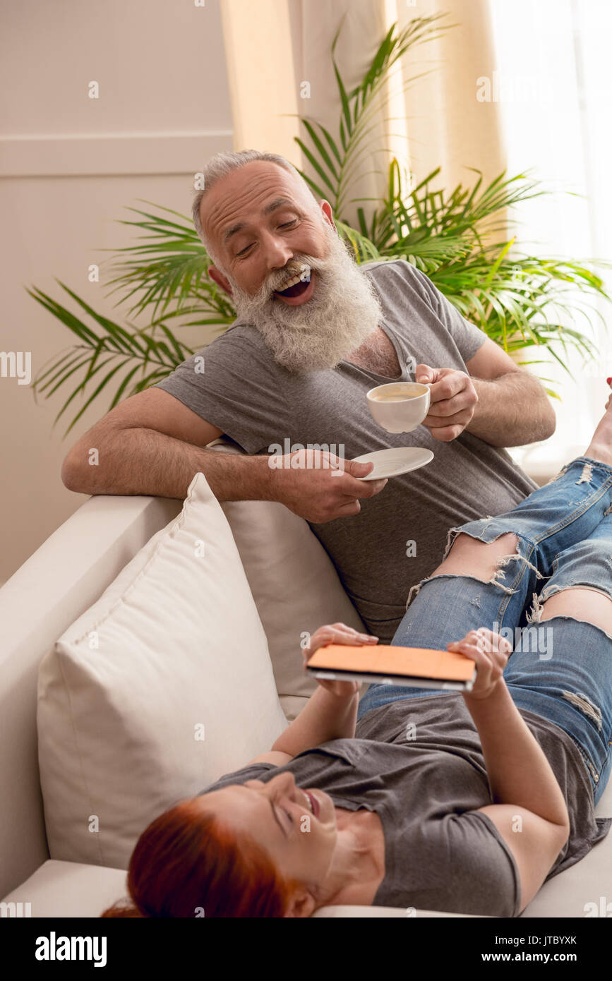 L'homme de boire du café et de l'épouse à l'aide de tablet tout en passant du temps ensemble Banque D'Images