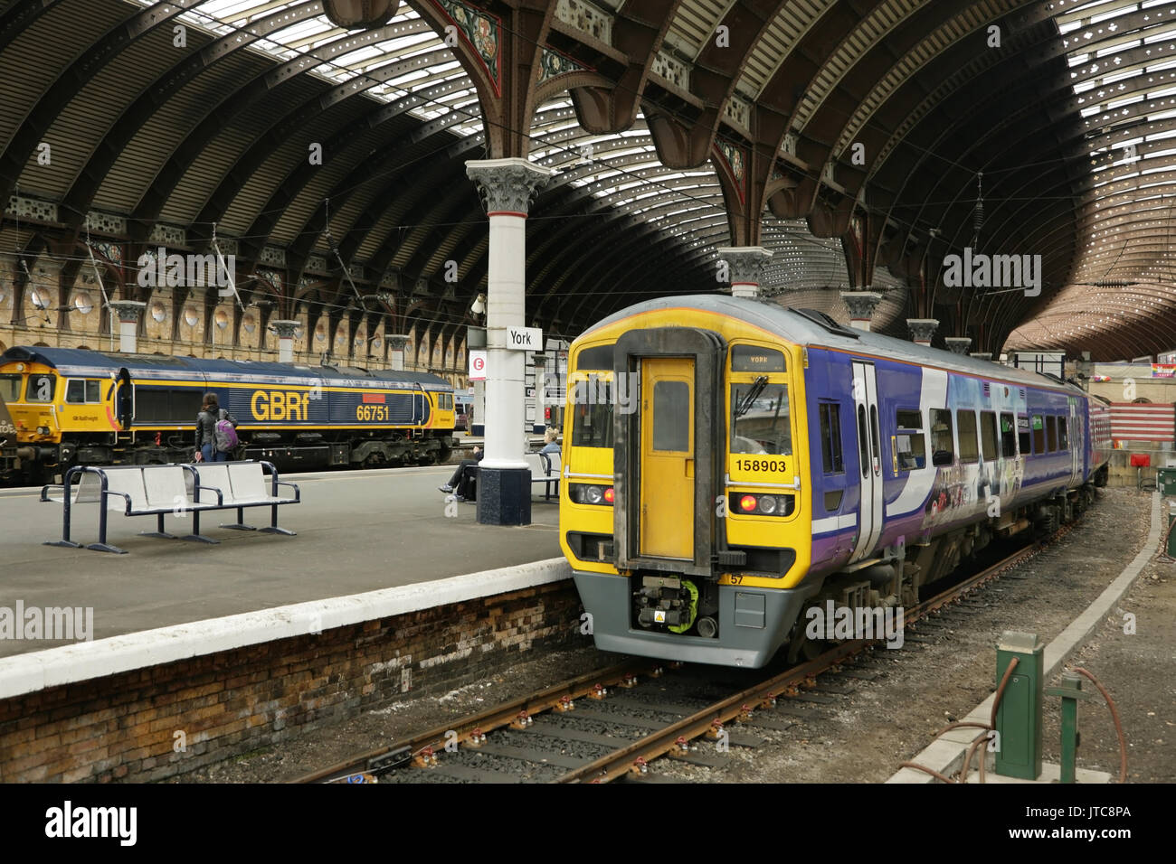 Northern rail diesel 158 classe debout à York, Royaume-Uni, tandis que la classe 66 66751 GBRF loco passe avec train de charbon en direction nord. Banque D'Images