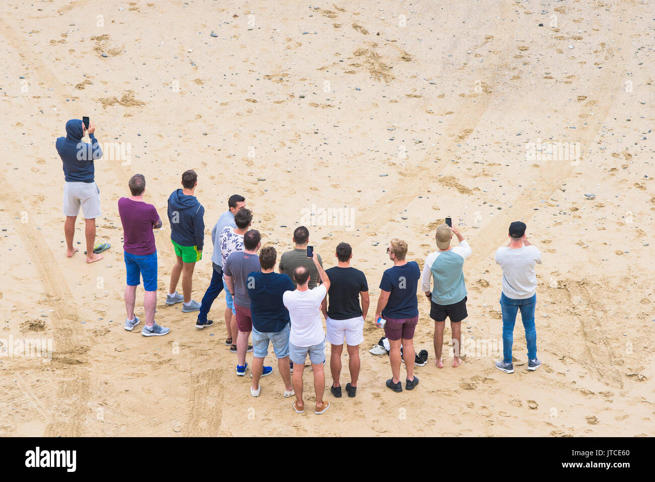 Une vue de dessus d'un groupe d'hommes debout sur une plage à l'aide des smartphones. Banque D'Images Une vue de dessus d'un groupe d'hommes debout sur une plage à l'aide des smartphones. Banque D'Images