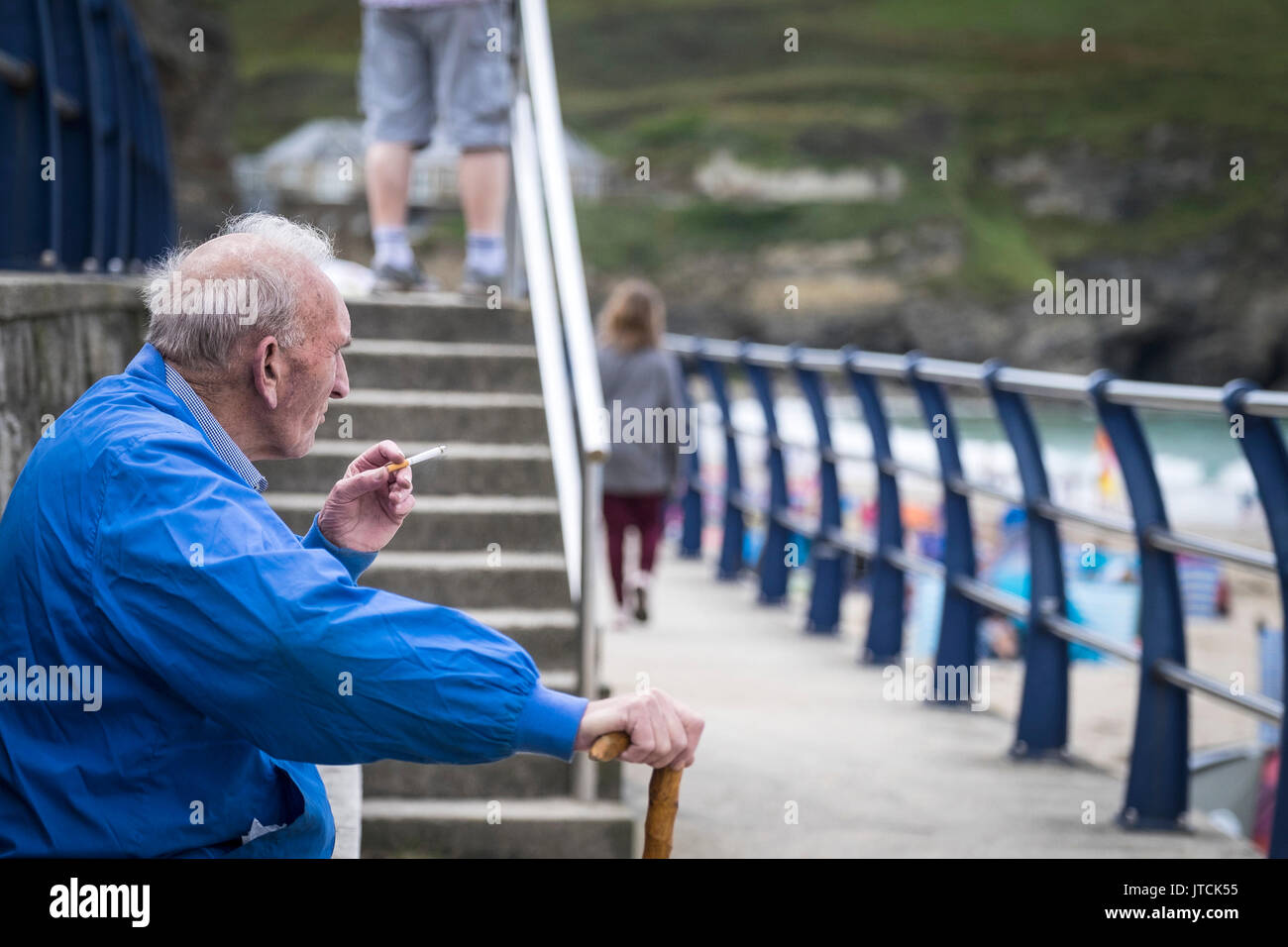 Un vacancier âgées fumer une cigarette et de détente à Portreath à Cornwall. Banque D'Images