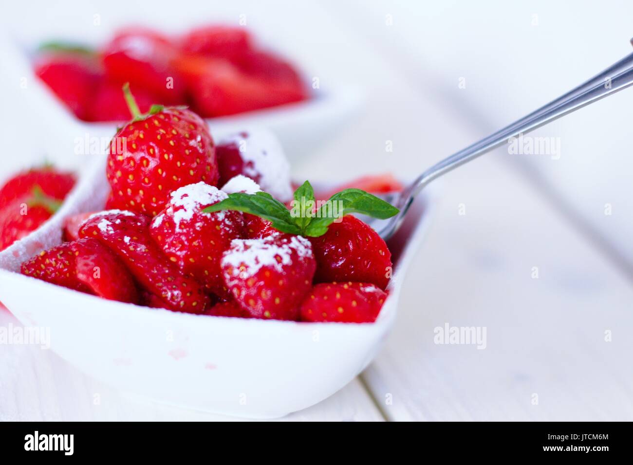 Les enfants jardin préféré snack - les fraises avec le sucre dans un bol carré blanc Banque D'Images