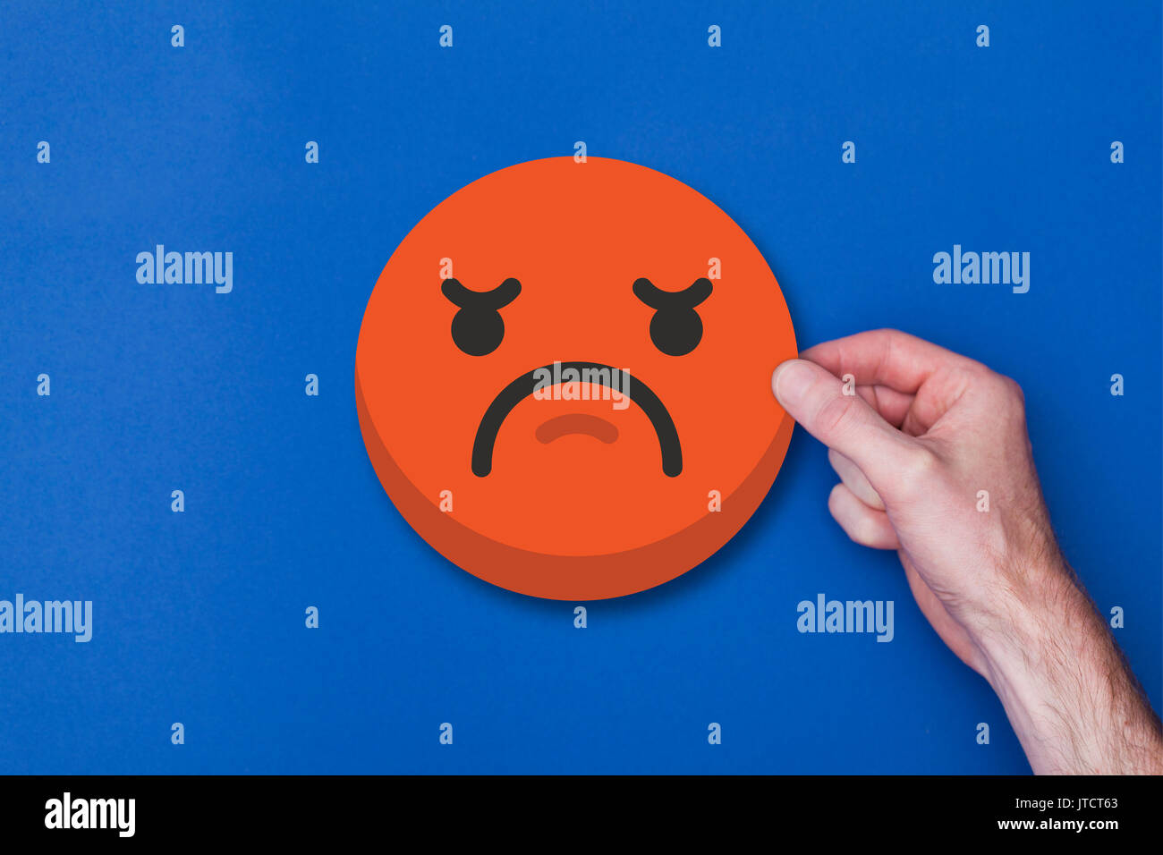 Homme main tenant une émoticône emoji icône smiley chef malheureux Banque D'Images