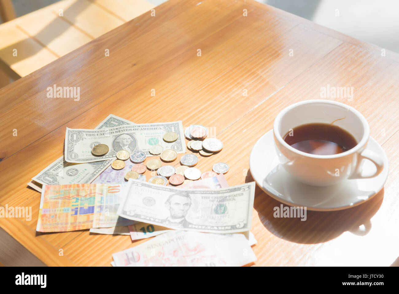 Faire de l'argent astuce dollar ou euro pour voyager et tasse de thé près de sur la table en bois Banque D'Images