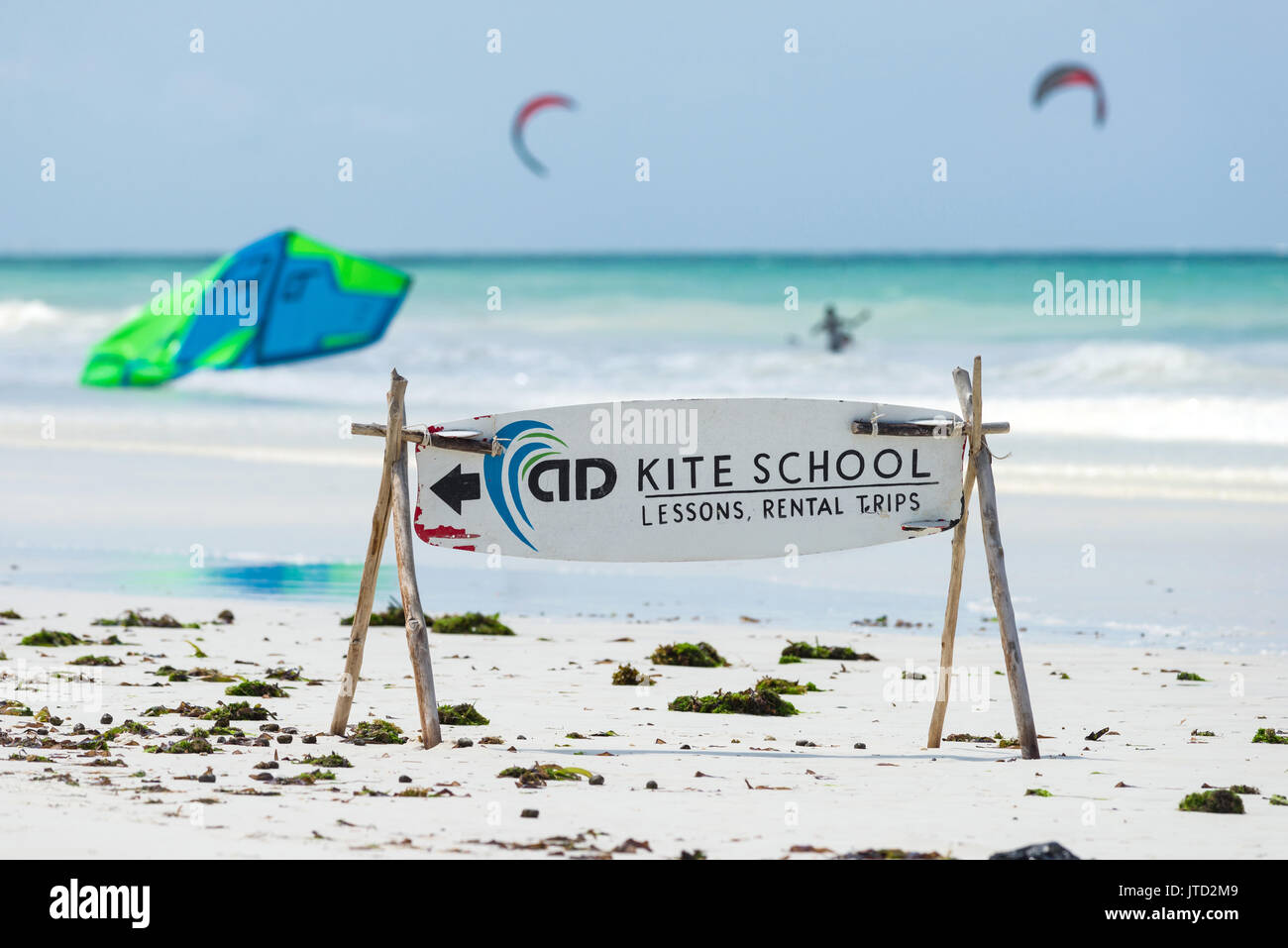 Ecole de Kite signe sur plage avec des kitesurfers dans l'océan en arrière-plan, Diani, Kenya Banque D'Images