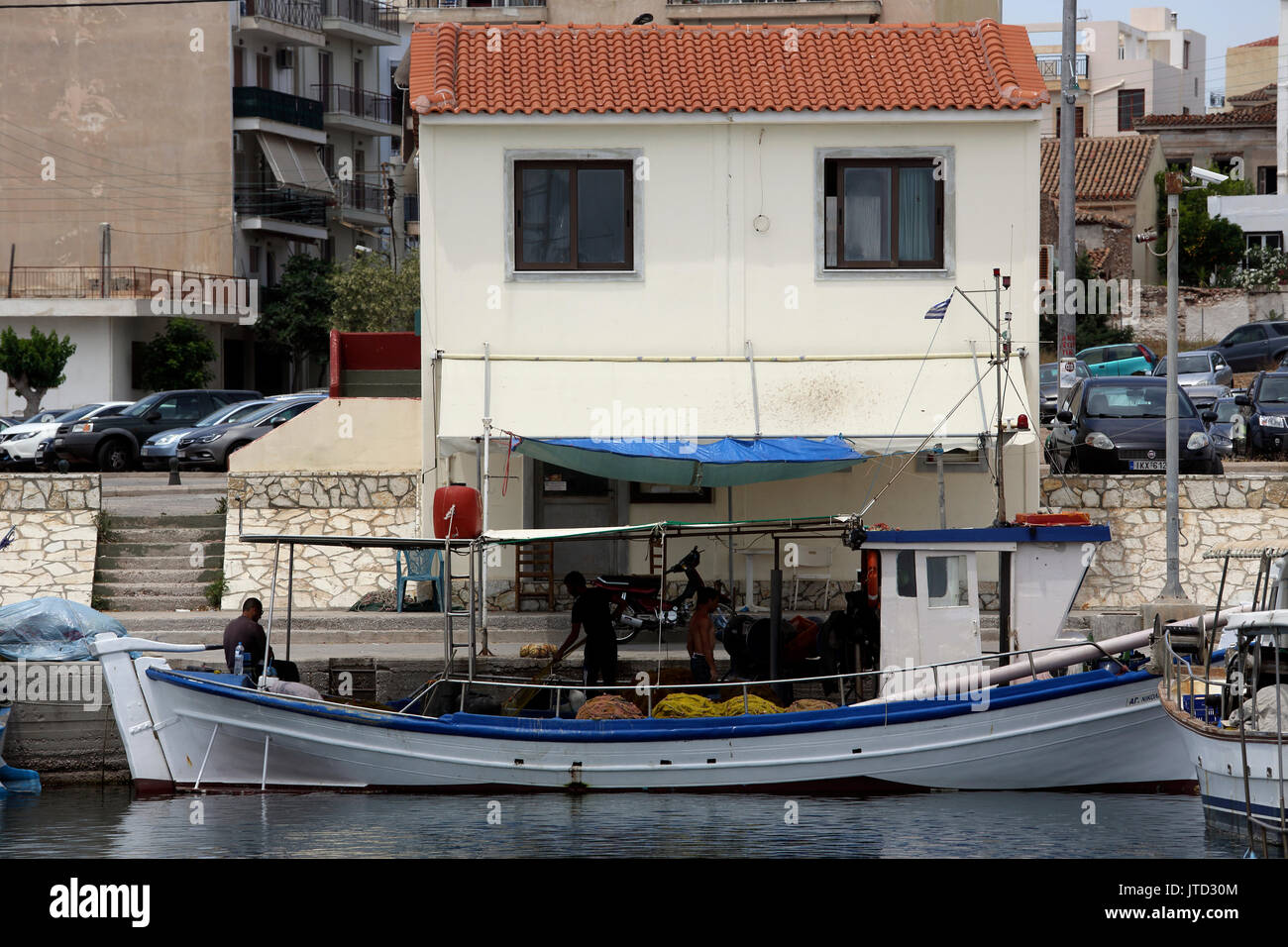 Port de Lavrio Grèce Attique hommes travaillant sur bateau de pêche près d'une maison Banque D'Images