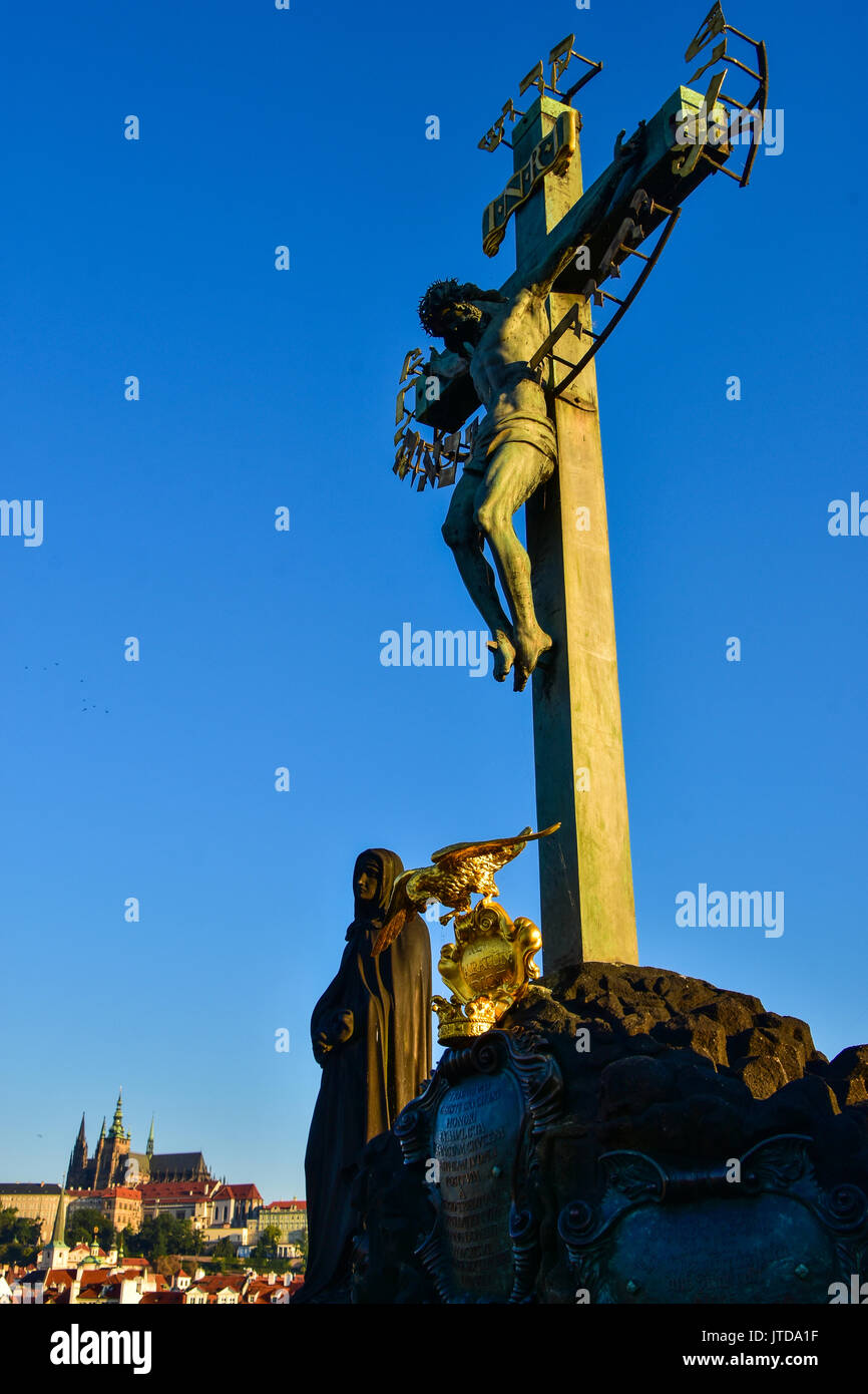 La statue du Christ sur la croix sur le pont Charles au coucher du soleil à Prague, République Tchèque Banque D'Images