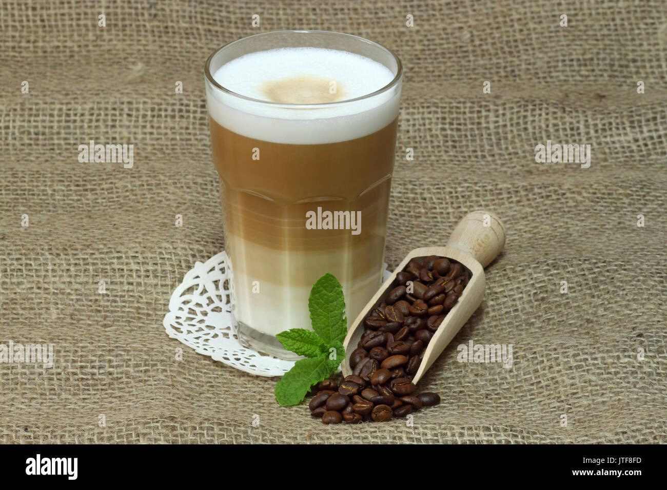Latte Macchiato en verre avec des grains de café sur fond brun Banque D'Images