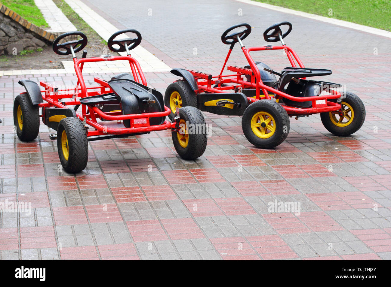 Deux vélos à quatre roues rouge sur la chaussée sur le parc Banque D'Images