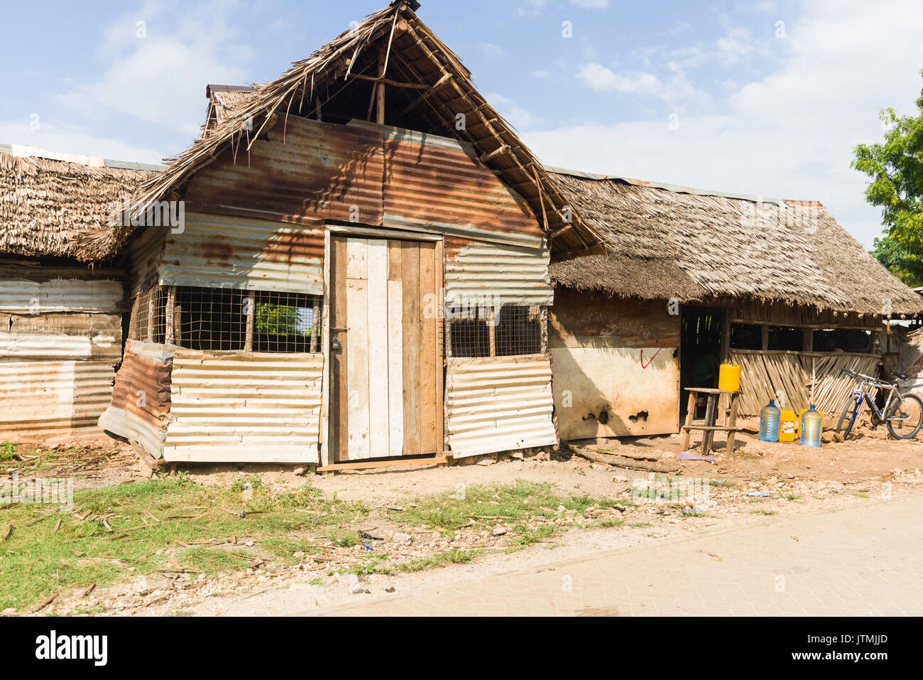 La tôle ondulée et cabane en bois avec des feuilles de palmier séchées un toit de chaume, au Kenya Banque D'Images
