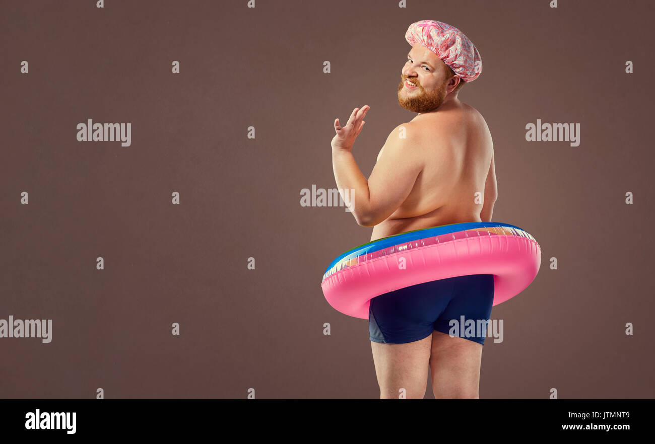 L'homme drôle de graisse dans un maillot de bain avec un cercle gonflable. Banque D'Images