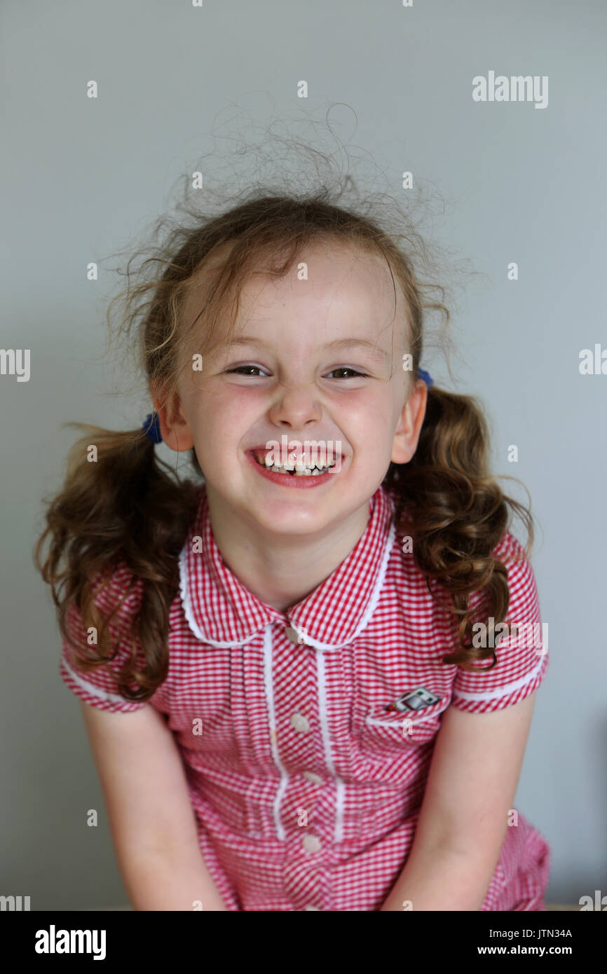 Isabelle, 5, photographié dans son uniforme de l'école après sa première dent est tombée à son domicile à Sussex, UK. Banque D'Images