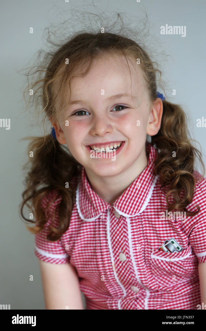 Isabelle, 5, photographié dans son uniforme de l'école après sa première dent est tombée à son domicile à Sussex, UK. Banque D'Images