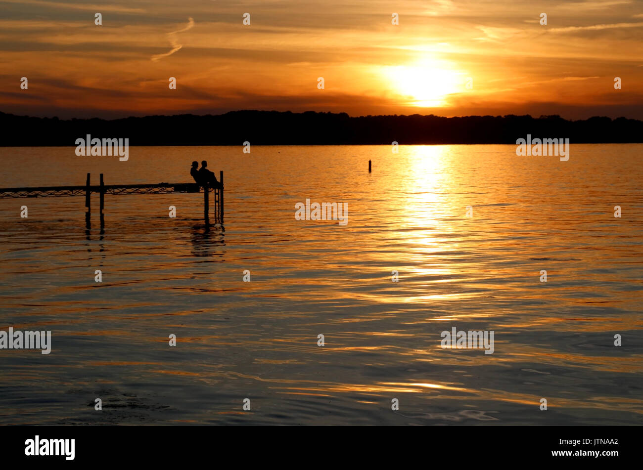 Paysage avec coucher du soleil doré et des silhouettes de personnes profitant de la belle soirée sur un lac Mendota pier dans la ville de Madison, Wisconsin, USA. Banque D'Images