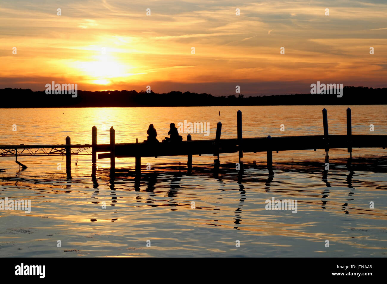 Paysage avec coucher du soleil doré et des silhouettes de personnes profitant de la belle soirée sur un lac Mendota pier dans la ville de Madison, Wisconsin, USA. Banque D'Images