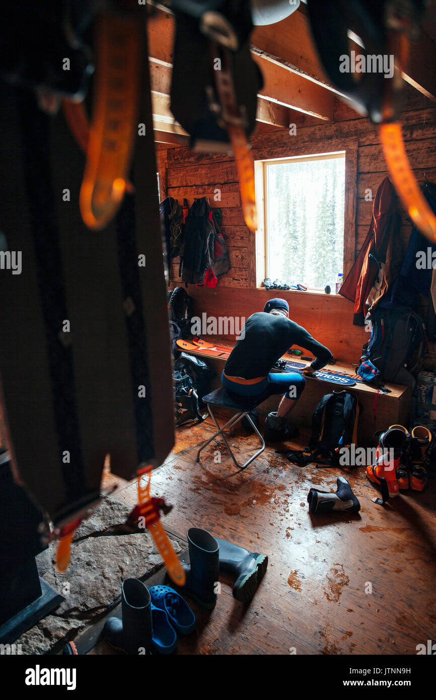 Un homme travaillant sur ses skis après une longue journée dans l'arrière-pays, Cascade Lodge. B.C. Banque D'Images