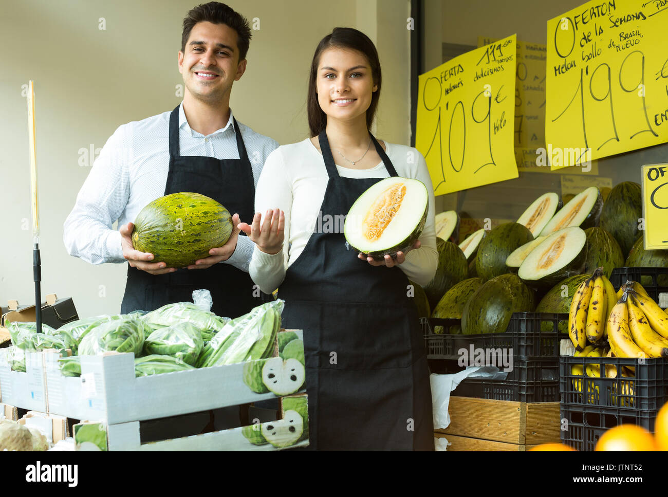 Cheerful young woman and man vente de melons frais sur market Banque D'Images