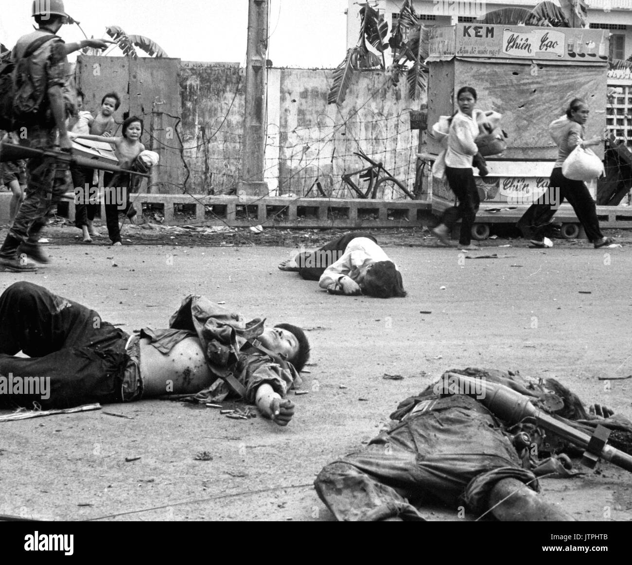 Avec la peur et l'appréhension montrant sur leur visage, et à la demande de troupes vietnamiennes du sud, les femmes et les enfants sont chargés de biens récupérés se précipitent au-delà du corps de trois Viet Cong tués dans les combats. Mai 1968. (USIA) DATE EXACTE INCONNUE SHOT #  FICHIER NARA : 306-MVP-4-4 LIVRE Guerres et conflits #  : 423 Banque D'Images