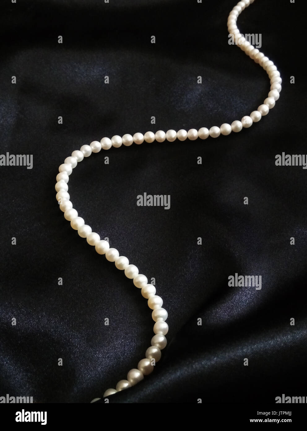 Perles blanches sur soie noire. Banque D'Images
