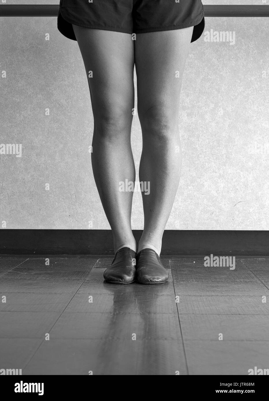 Version noir et blanc des jambes d'une danseuse de jazz en première position à la barre dans la catégorie jazz Banque D'Images
