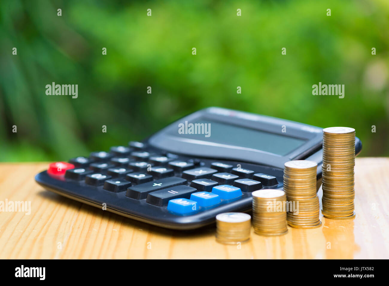 De plus en plus d'épargne, des crédits et une calculatrice sur bois avec arbre vert arrière-plan flou. La croissance financière, d'économiser de l'argent, la richesse et le succès de l'entreprise financement de co Banque D'Images