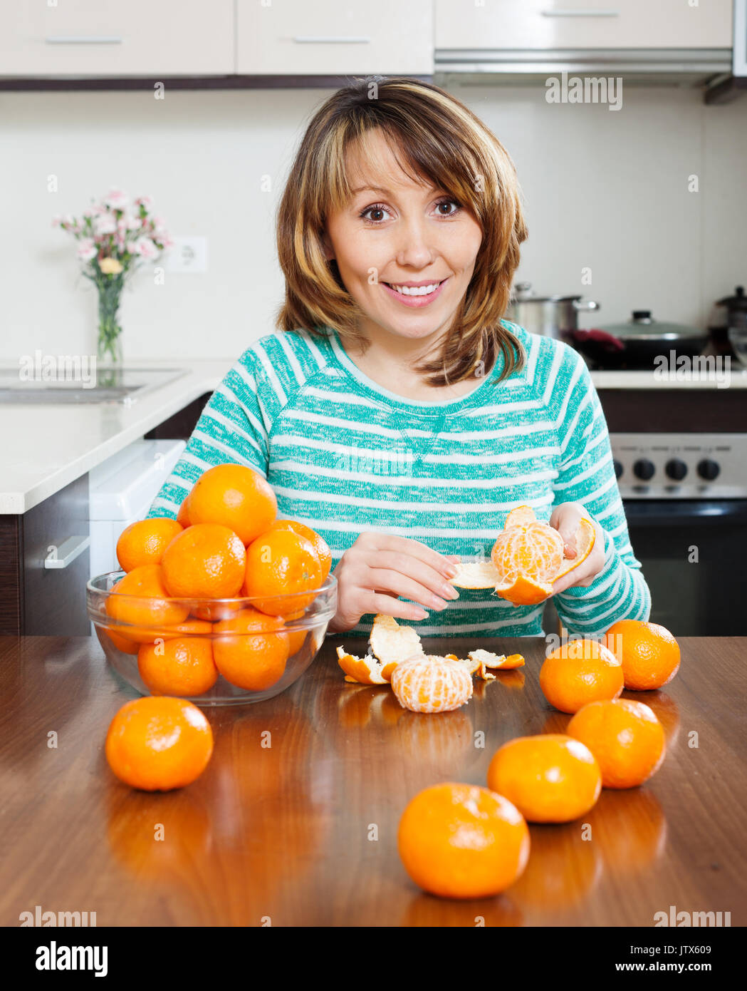 Femme avec des mandarines dans la cuisine Banque D'Images