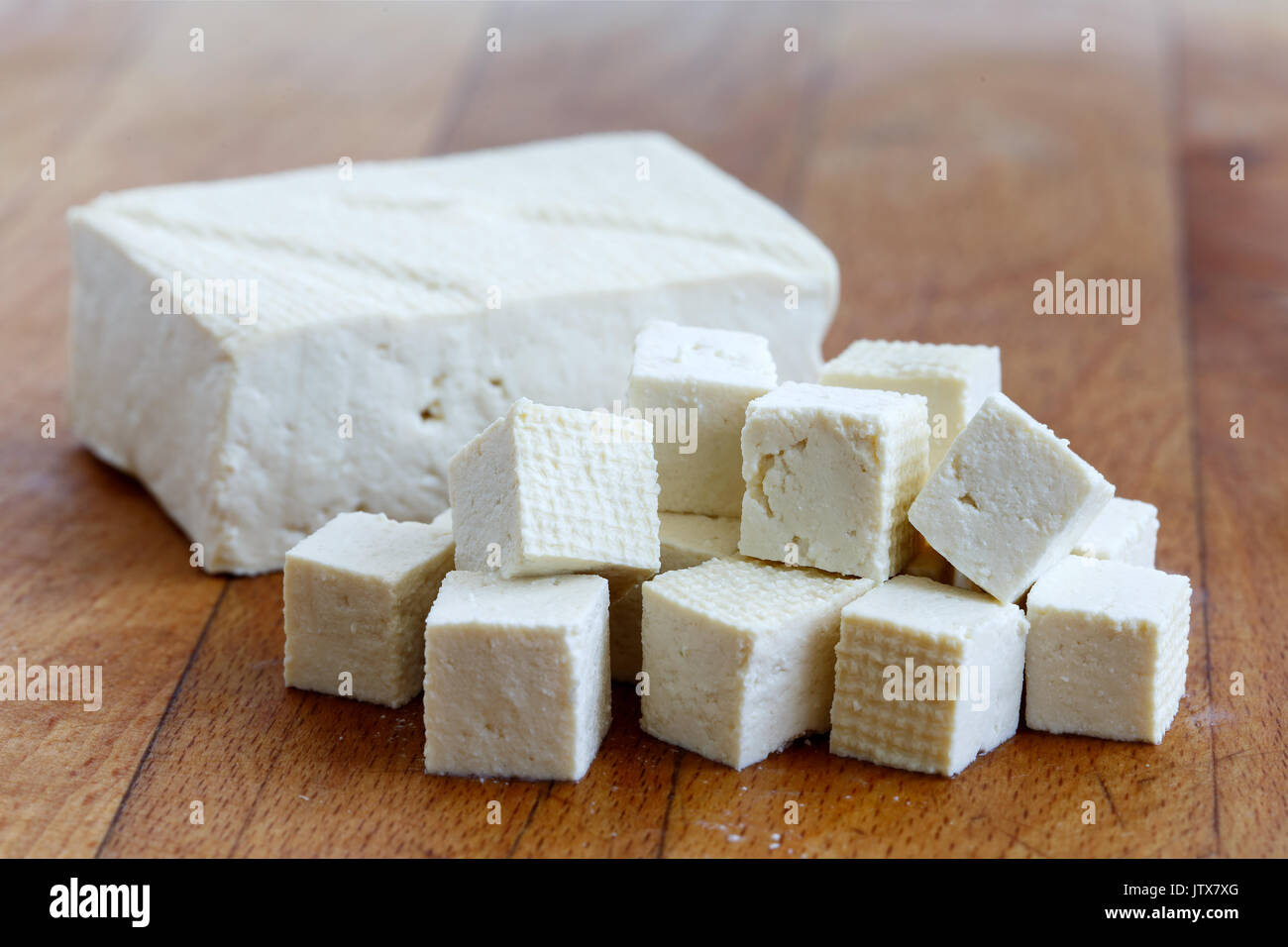 Un bloc de tofu blanc avec des cubes de tofu couper planche à découper en bois. Banque D'Images