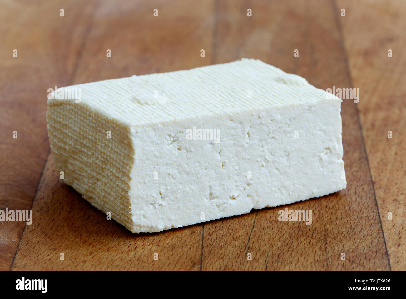 Un bloc de tofu blanc sur la planche à découper en bois. Banque D'Images
