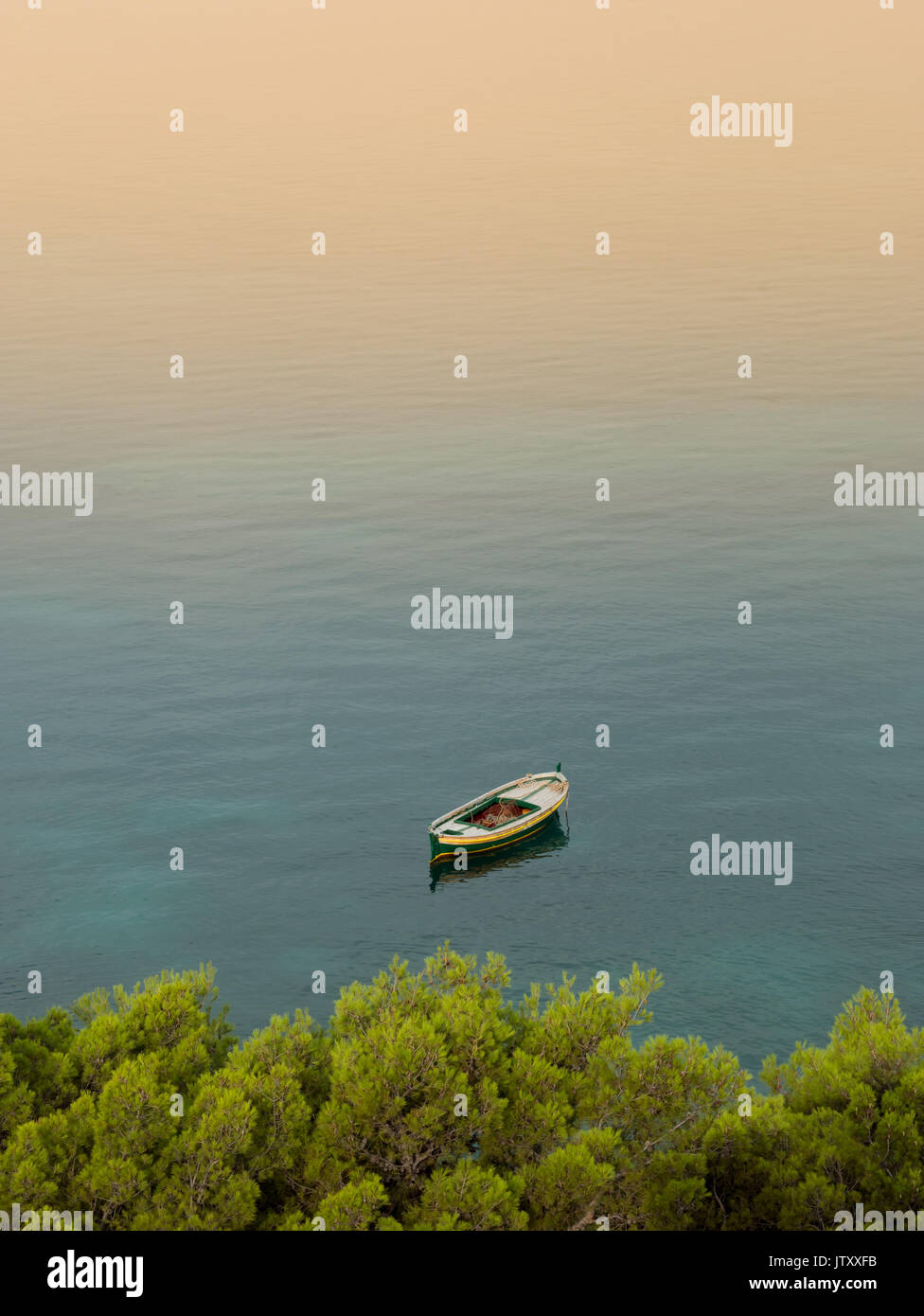 Petit bateau en bois sur l'ancre au lever du soleil près de la côte méditerranéenne Banque D'Images