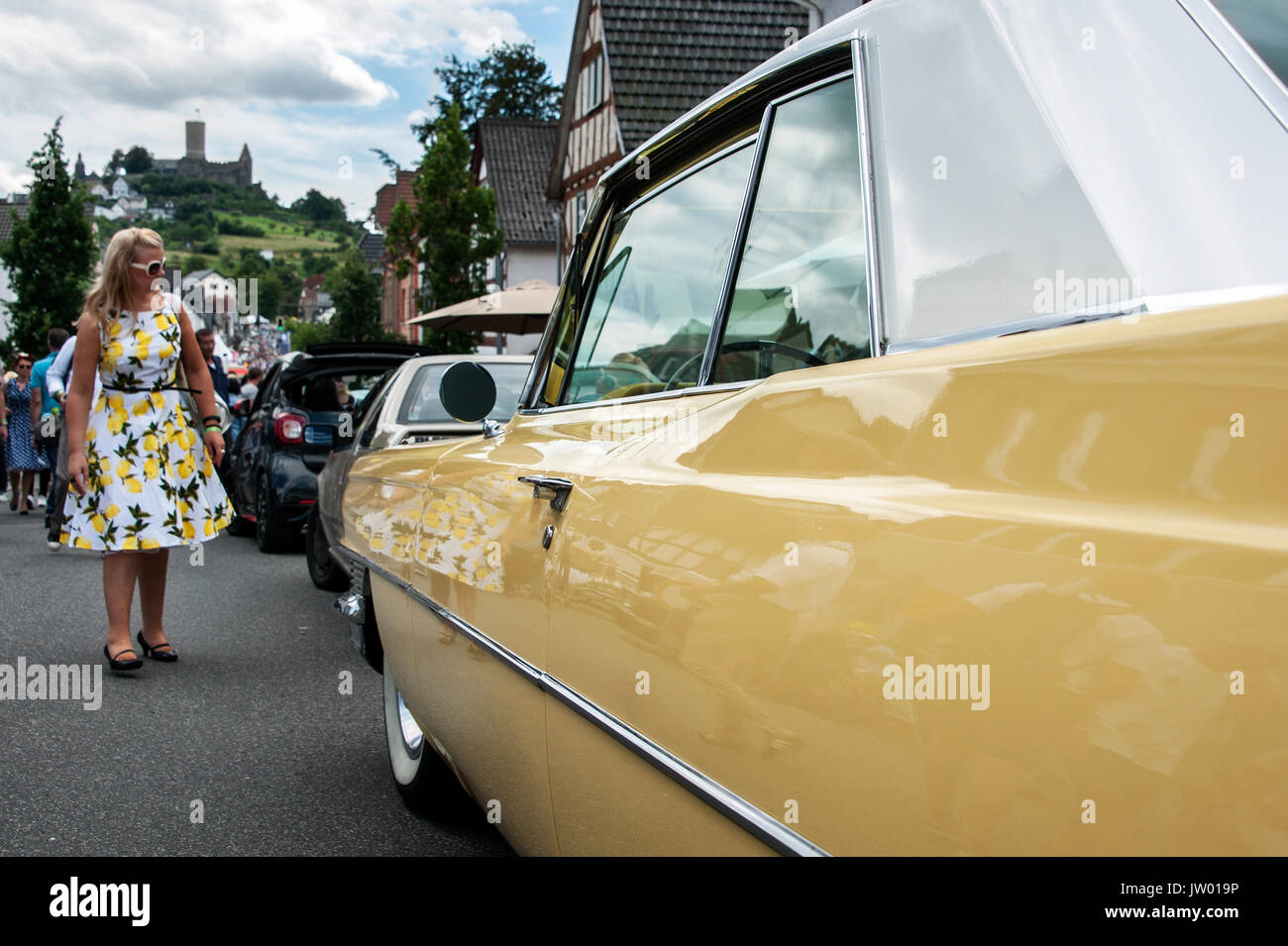 Vintage Car festival 'golden oldies', femme vêtue de années 50 look et une voiture jaune sur la rue principale au-dessous du château. Banque D'Images