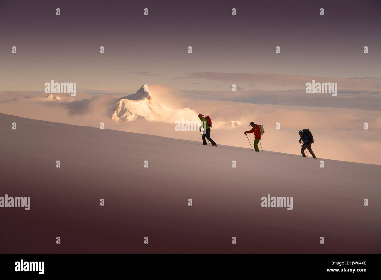 Trois alpinistes ski Denali croissant, avec le coucher du soleil sur le mont Hunter dans l'arrière-plan. Denali National Park est un endroit idéal pour le ski de randonnée et l'escalade tours. Banque D'Images