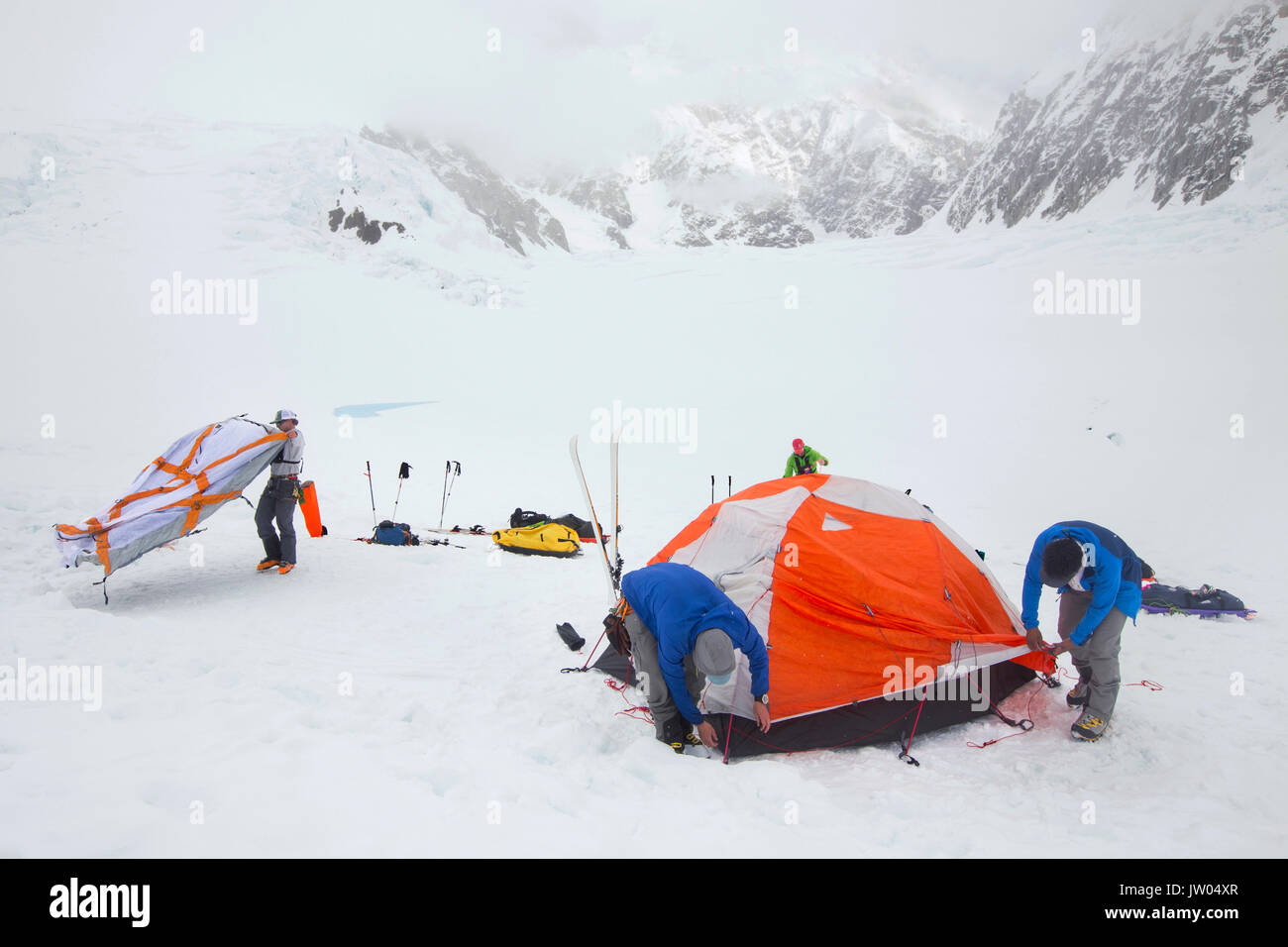 Les alpinistes sont de mettre en place des tentes dans un blizzard sur la partie inférieure du glacier Kahiltna sur Denali en Alaska. Banque D'Images