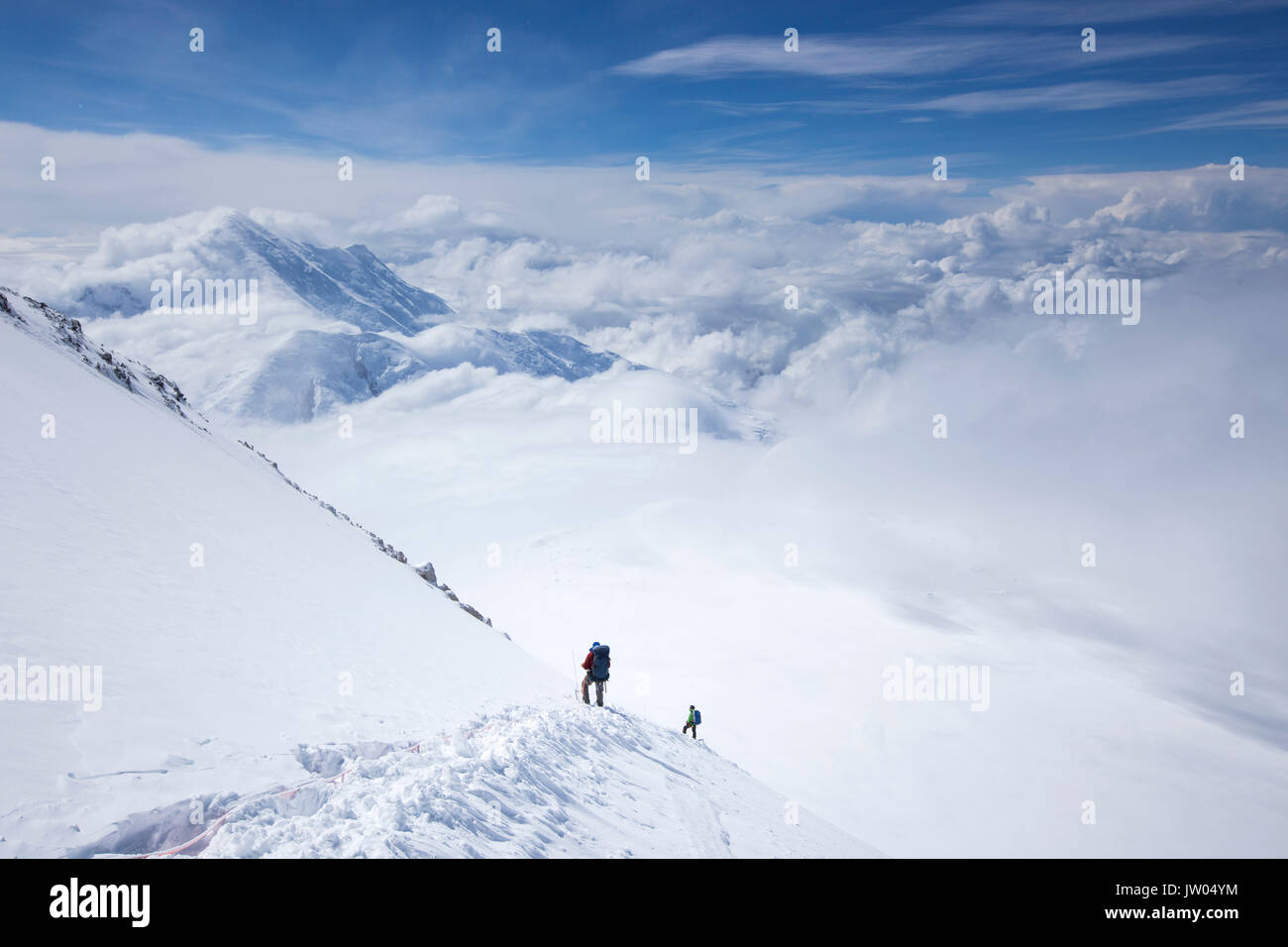 Les alpinistes descendent de Denali Pass avec camp d'altitude dans la distance. Denali en Alaska, est le plus haut sommet d'Amérique du Nord. Banque D'Images