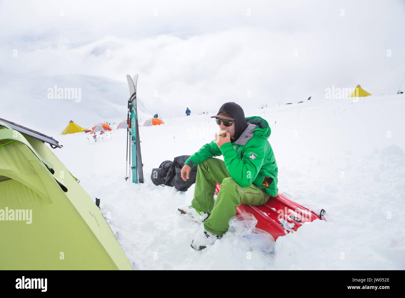 L'alpiniste est de manger une collation dans un camp à 4000 m sur Denali, en Alaska. Banque D'Images