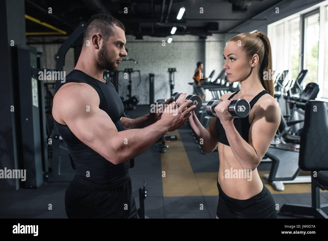 Young caucasian couple d'athlètes de la formation avec les haltères à gym ensemble Banque D'Images