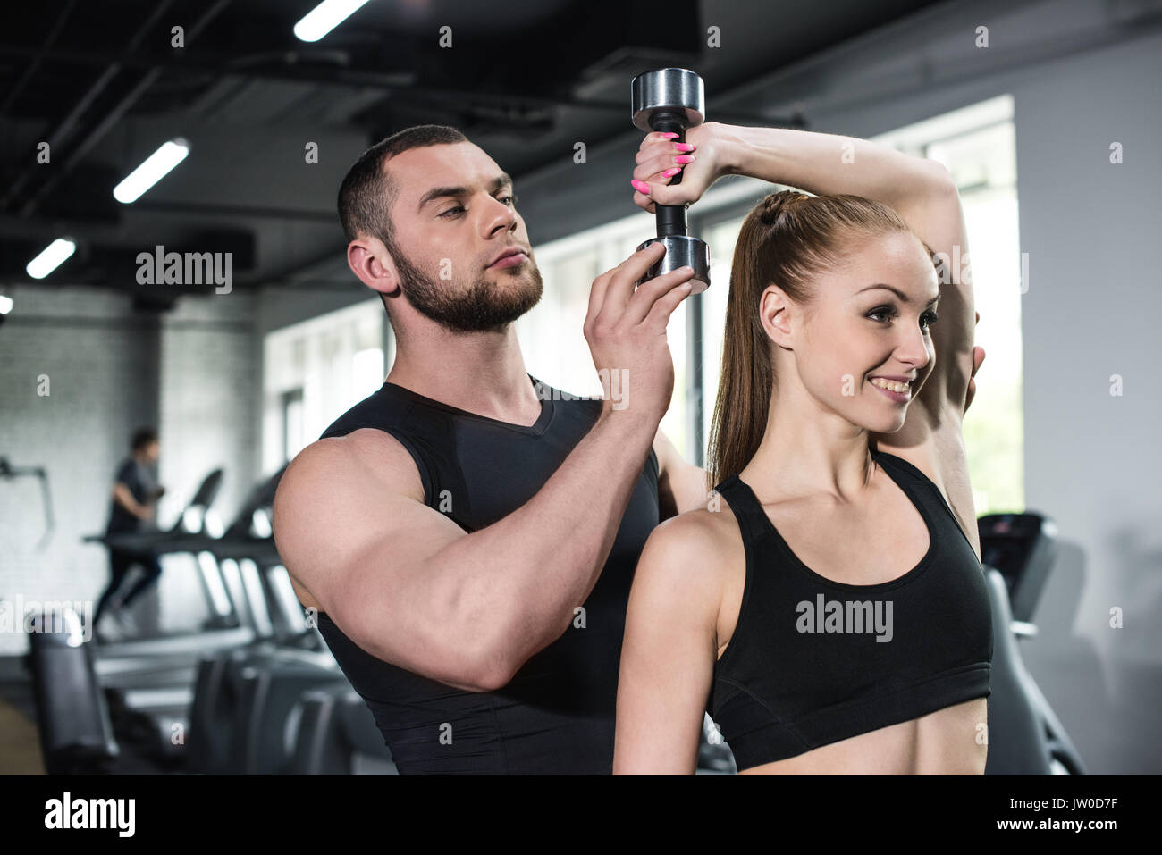 Aider les jeunes instructeurs smiling woman with dumbbell at gym Banque D'Images