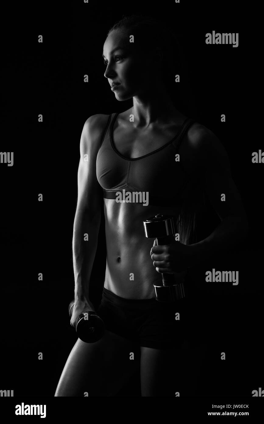 Formation sportive musculaire avec haltères isolé sur le noir, le noir et blanc Banque D'Images