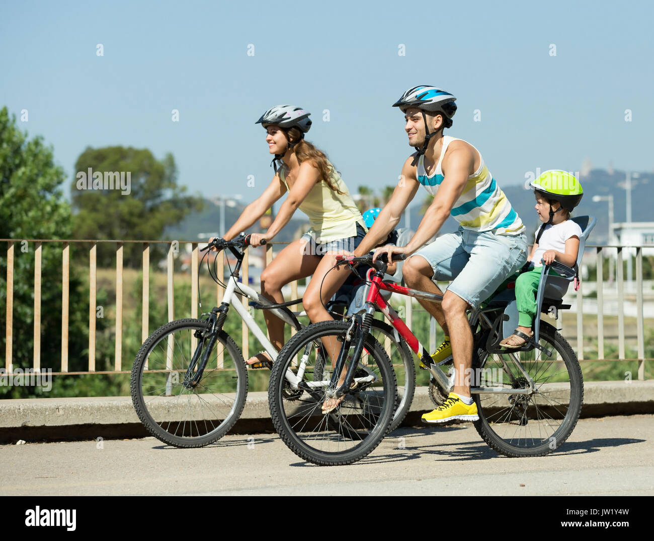 Les jeunes de la famille active de quatre à vélo sur route dans la rue journée d'été Banque D'Images