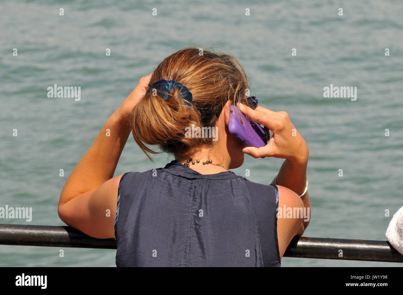 Une femme dame fille en utilisant un téléphone mobile à la mer smartly  dressed avec cheveux attachés en arrière et attrayants portant des lunettes  de soleil à la réflexion Photo Stock -
