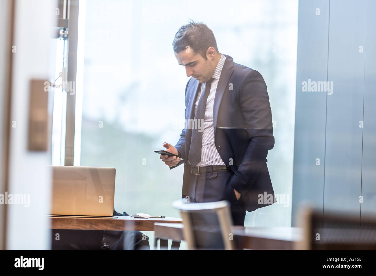 Businessman looking at smart phone in modern bureau d'entreprise. Banque D'Images