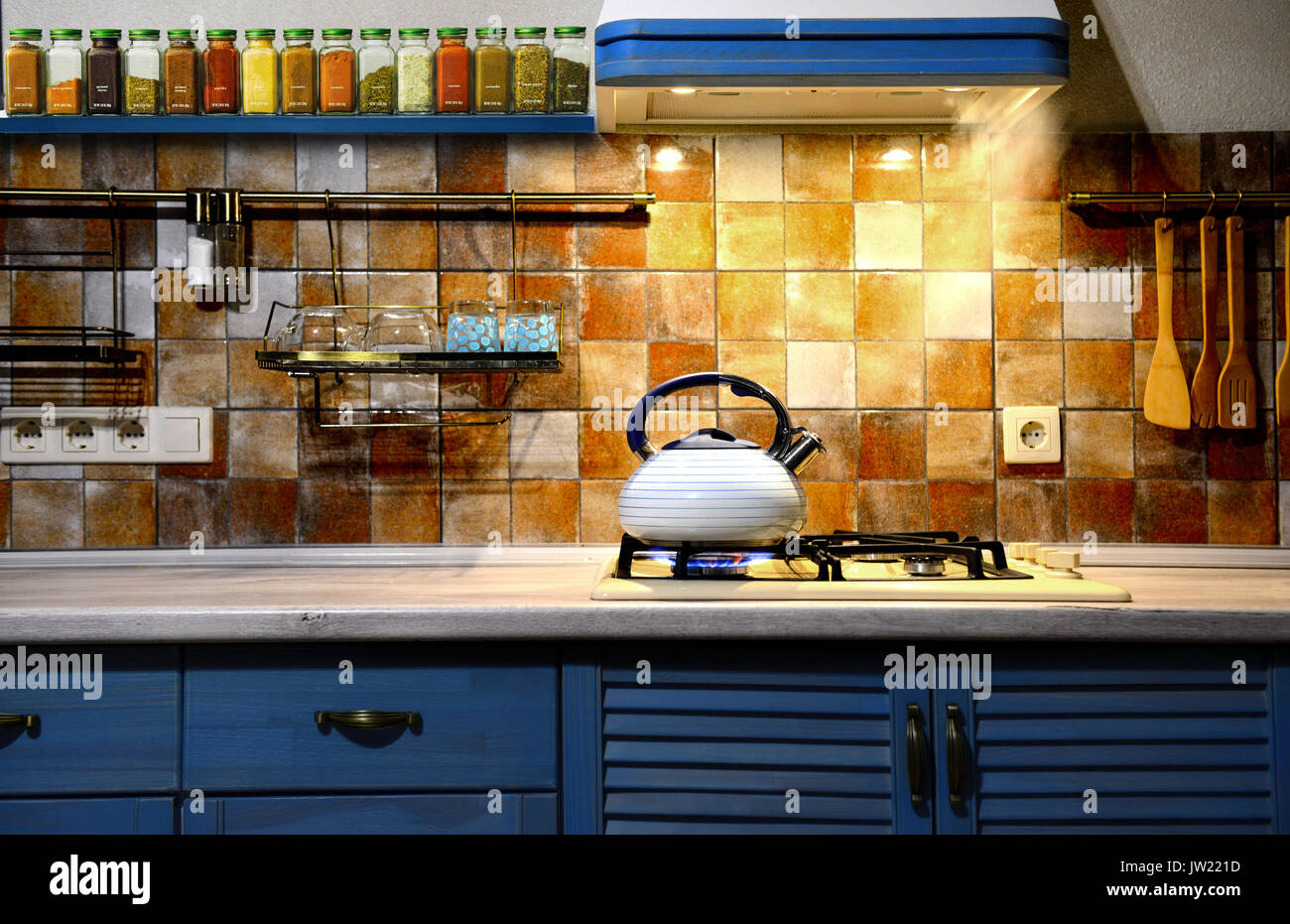 Bouilloire sifflante en métal dans la cuisine d'ébullition. La cuisine moderne est bleu. Banque D'Images
