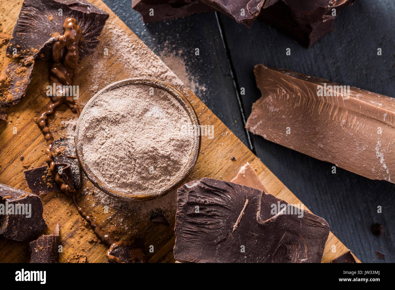 Diverses pièces en chocolat et le chocolat en poudre sur une planche à découper Banque D'Images