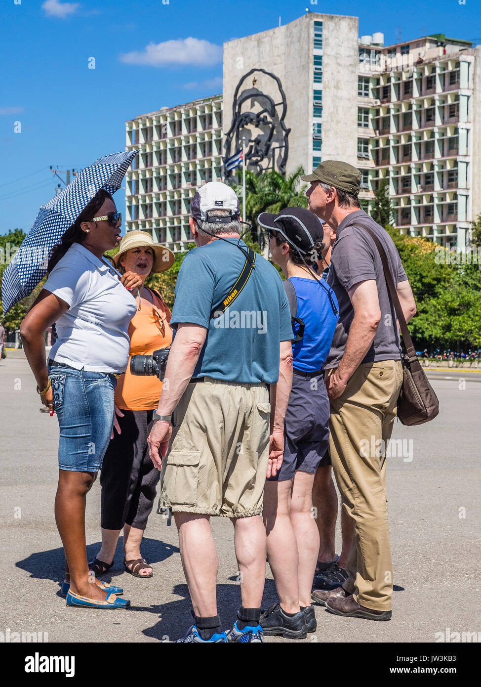 Une femme guide cubain sous un parasol sur la place de la Révolution présente l'histoire et l'importance de la place à un petit groupe d'hommes et femmes Banque D'Images