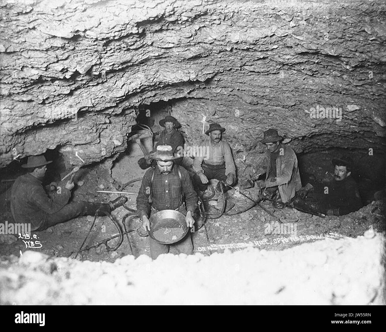 Dans cette image historique datant des environs de 1898, les mineurs de Gold Hill, territoire du Yukon, utilisent la vapeur pour décongeler le sol gelé dans une mine d’or souterraine éclairée à la bougie. La scène capture les conditions difficiles de l'exploitation minière dans la région pendant la ruée vers l'or du Klondike. Banque D'Images