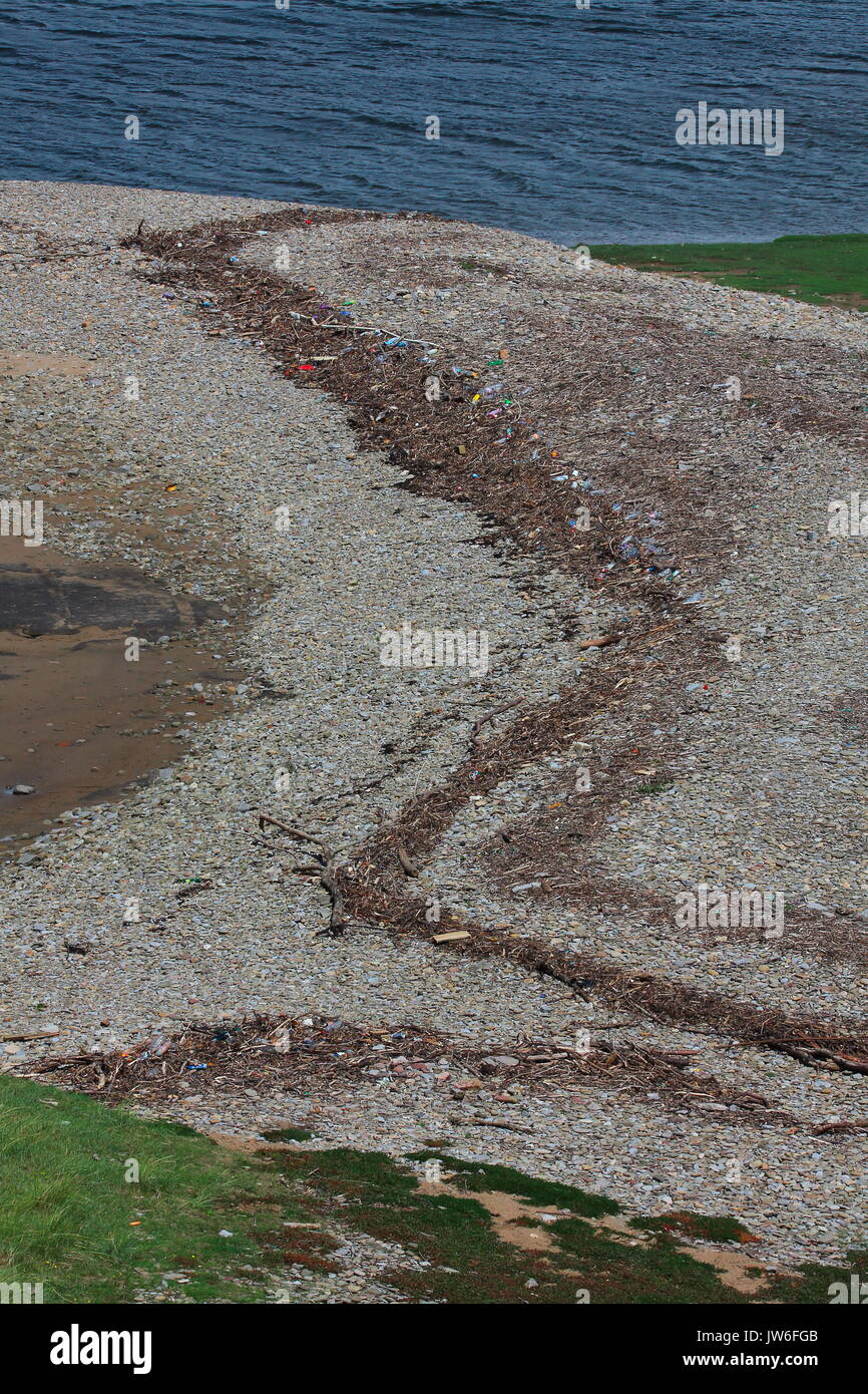 Une tache dans le paysage est l'ensemble de ces bouteilles en plastique et autres articles qui ont été déposés sur une banque de galets dans un petit estuaire. Banque D'Images