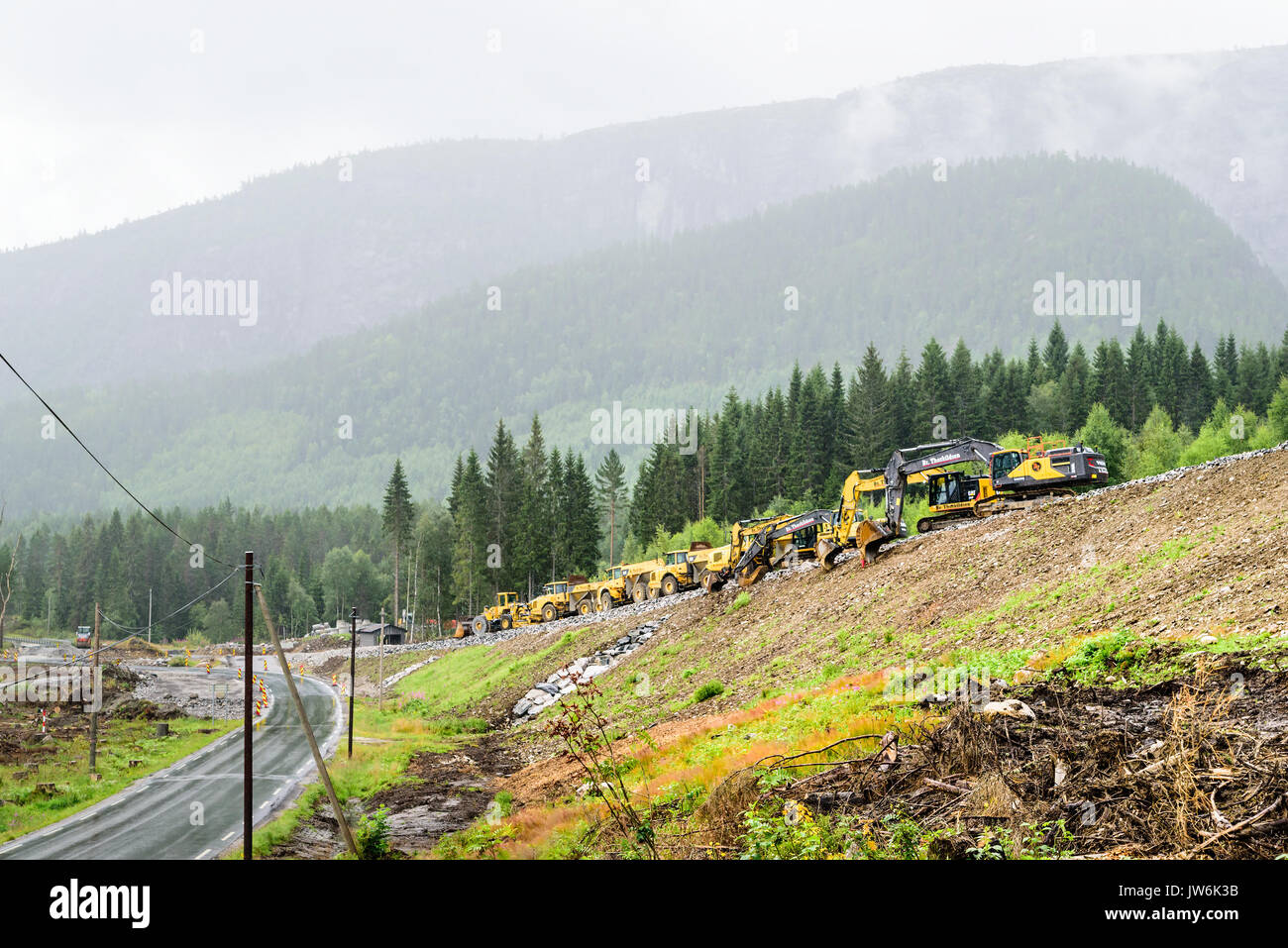 Lindesnes, Norvège - 1 août 2017 : Voyage documentaire de travaux routiers Véhicules en paysage montagneux, un jour de pluie. La haute montagne en arrière-plan. Banque D'Images