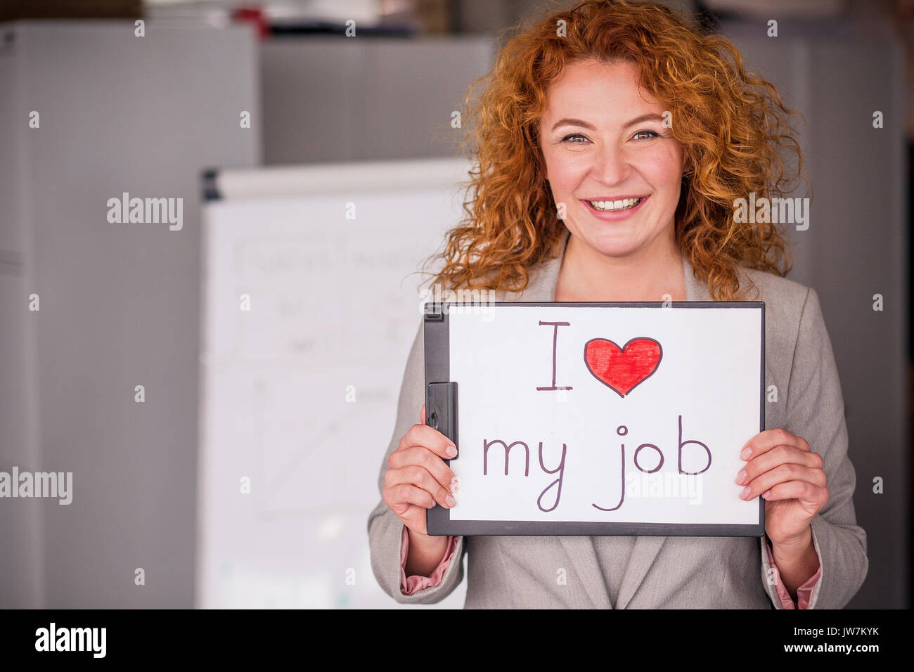 Red haired smiling businesswoman holding petite affiche. Banque D'Images