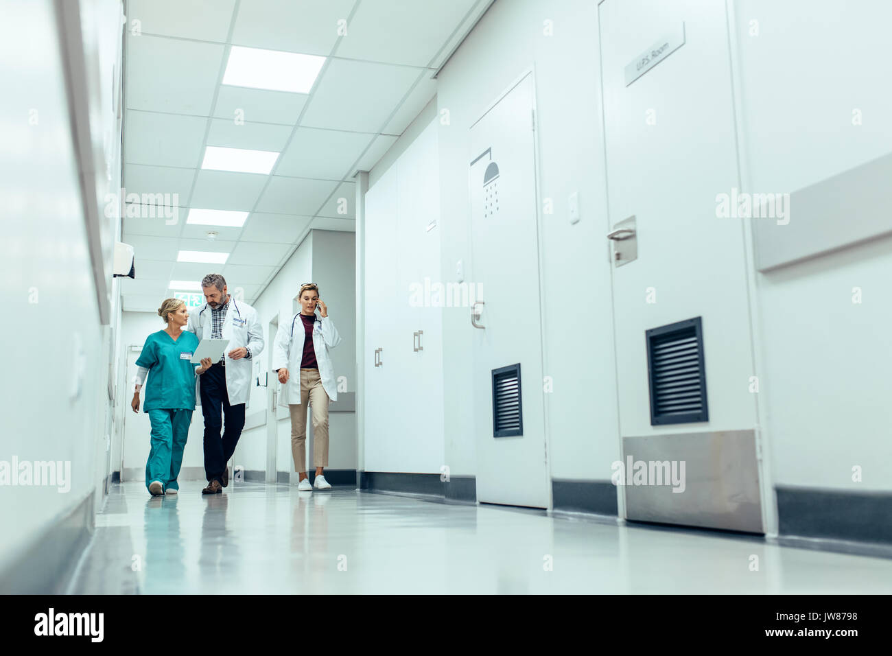 Longueur totale de l'équipe médicale de marcher dans le couloir de l'hôpital. Les médecins avec walking in hospital corridor et de discussions. Banque D'Images
